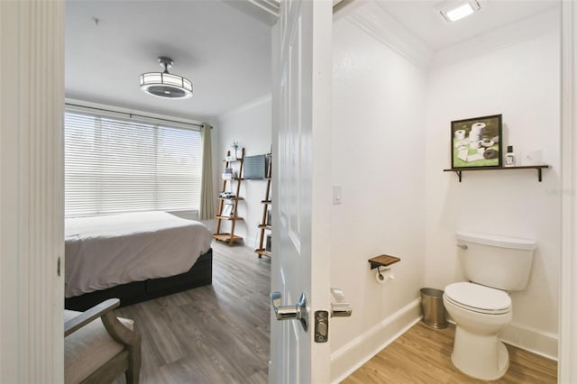 bathroom with toilet, crown molding, and hardwood / wood-style flooring