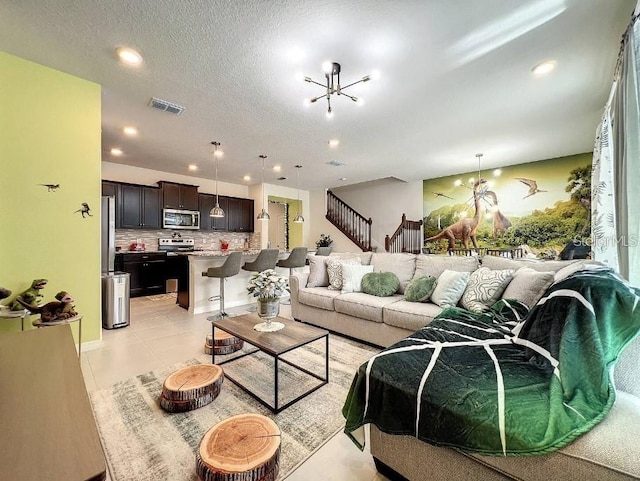 living room featuring a notable chandelier, light tile patterned flooring, and a textured ceiling