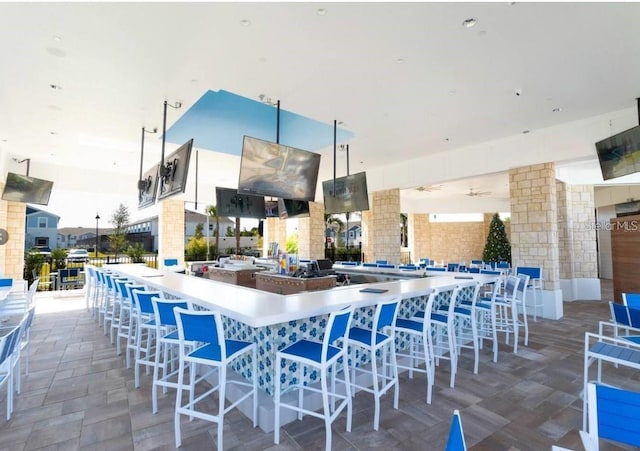 exterior space featuring ceiling fan, white cabinetry, and a kitchen bar