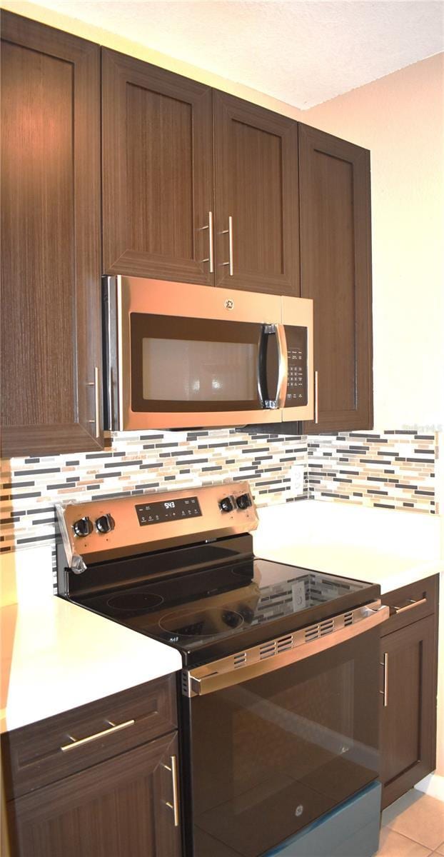 kitchen with backsplash, stainless steel appliances, and light tile patterned flooring