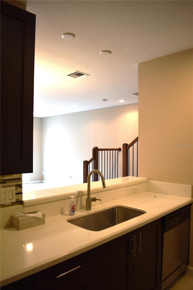 kitchen featuring dishwasher, dark brown cabinets, sink, and a textured ceiling