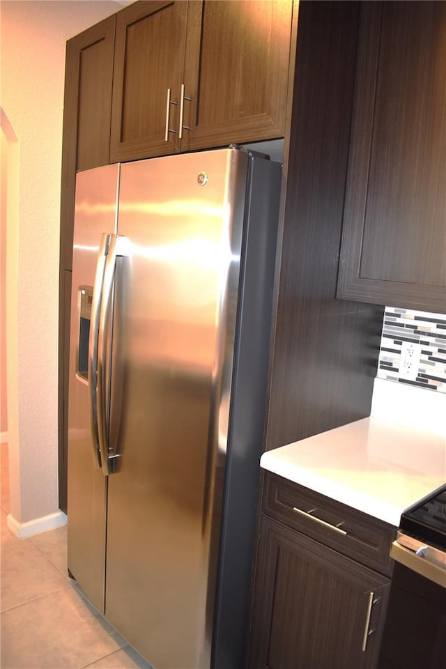 kitchen with decorative backsplash, light tile patterned flooring, and stainless steel refrigerator with ice dispenser