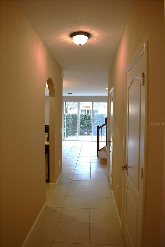 hallway with light tile patterned floors and a textured ceiling