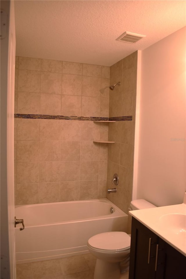 full bathroom featuring tiled shower / bath combo, vanity, a textured ceiling, tile patterned floors, and toilet