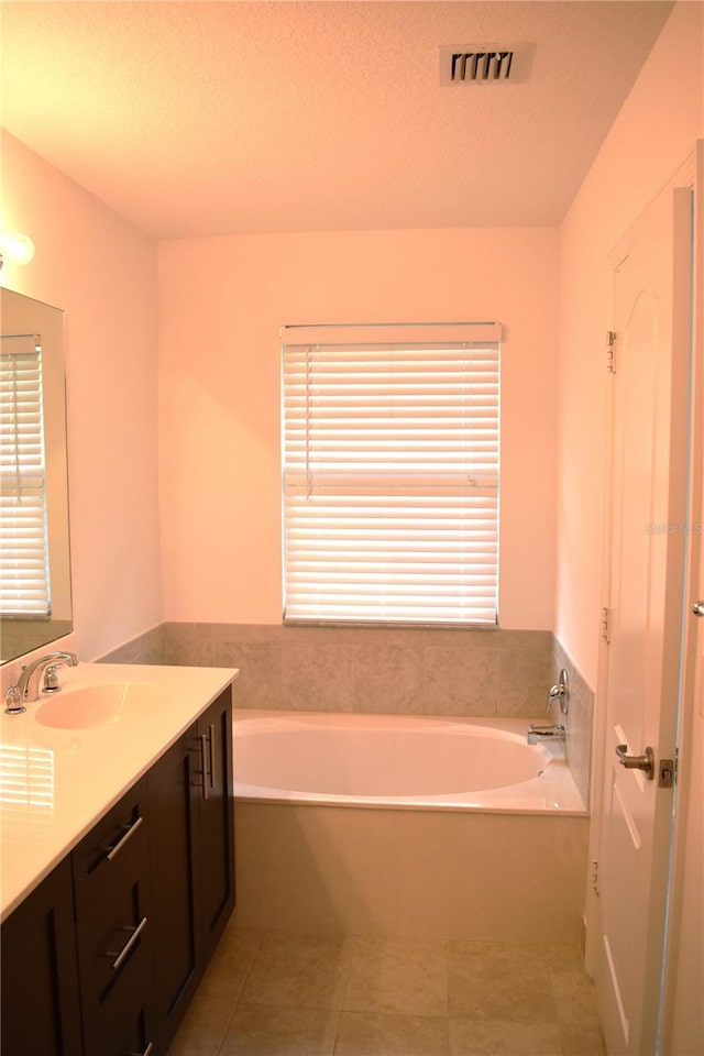 bathroom with tile patterned floors, vanity, and a washtub