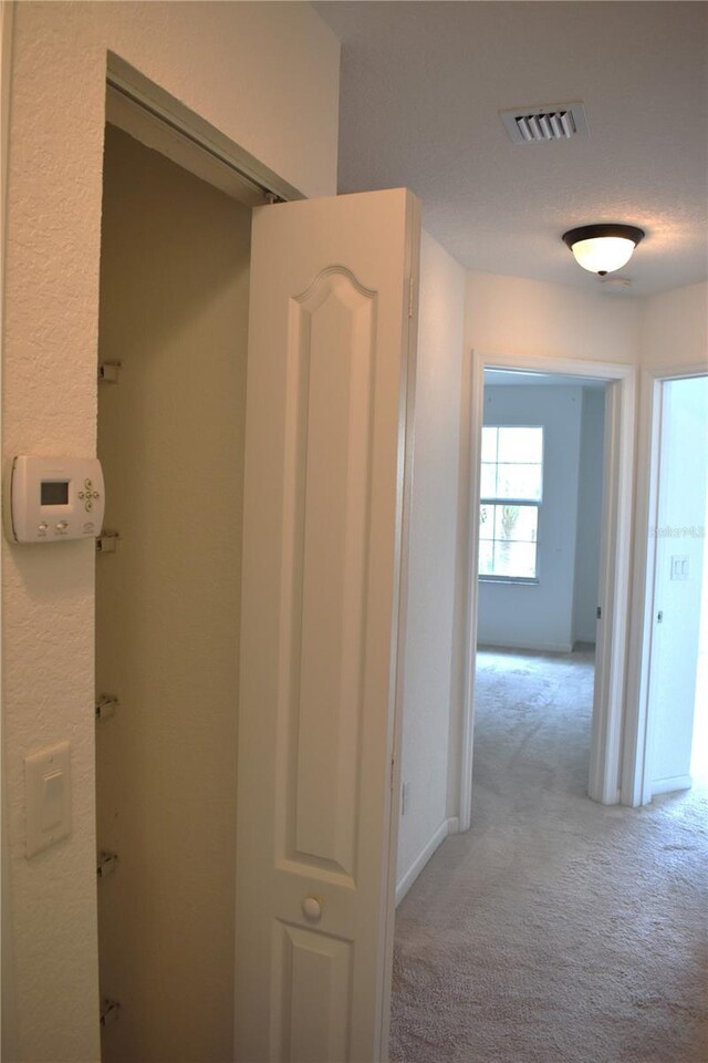 hallway featuring light colored carpet