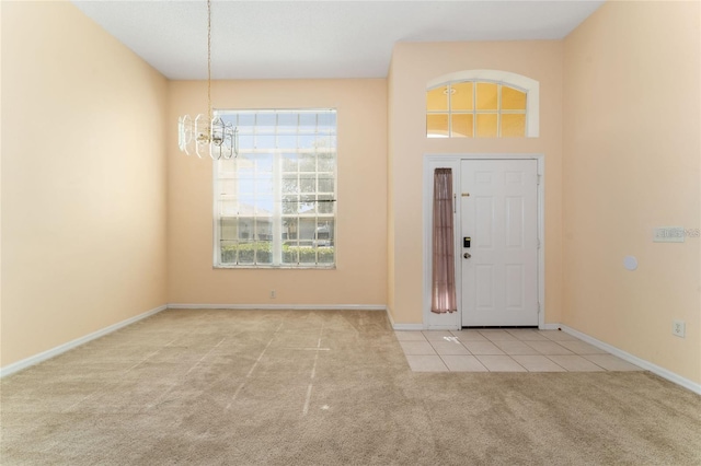 foyer entrance with light colored carpet and an inviting chandelier