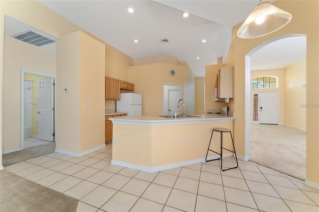 kitchen with white fridge, kitchen peninsula, light colored carpet, and sink