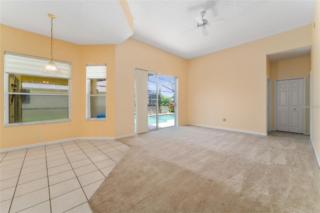 unfurnished living room with a textured ceiling, ceiling fan, and light tile patterned floors