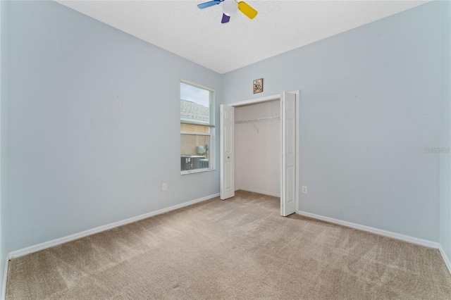 unfurnished bedroom featuring ceiling fan, light colored carpet, and a closet