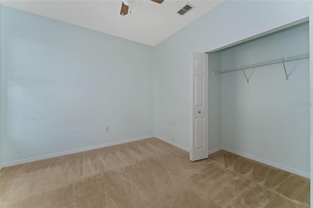 unfurnished bedroom with ceiling fan, light colored carpet, and a closet