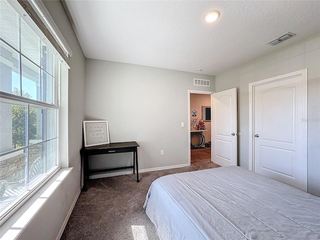 bedroom with a textured ceiling and dark colored carpet