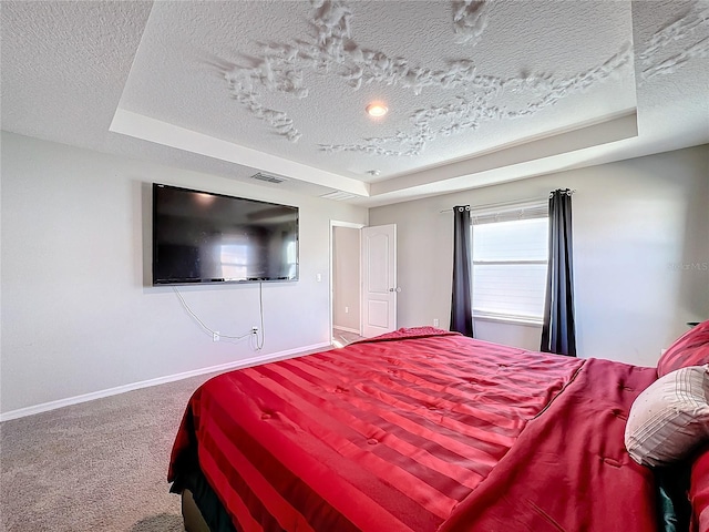 carpeted bedroom with a raised ceiling and a textured ceiling