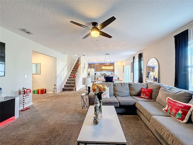 carpeted living room with ceiling fan and a textured ceiling