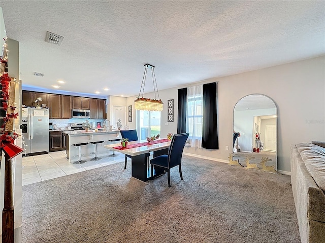 dining area featuring light carpet and a textured ceiling