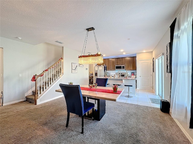 carpeted dining space with sink and a textured ceiling