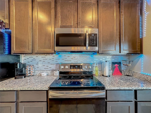 kitchen with light stone counters, backsplash, tile patterned flooring, and stainless steel appliances