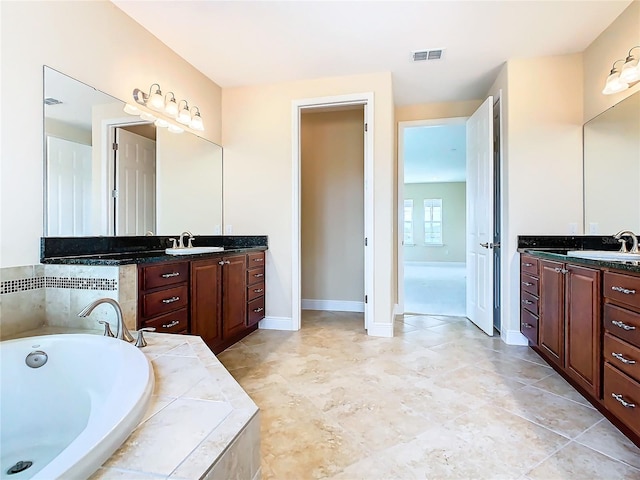 bathroom with tiled tub and vanity