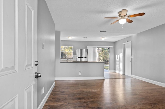 unfurnished living room featuring a textured ceiling, dark hardwood / wood-style floors, ceiling fan, and sink