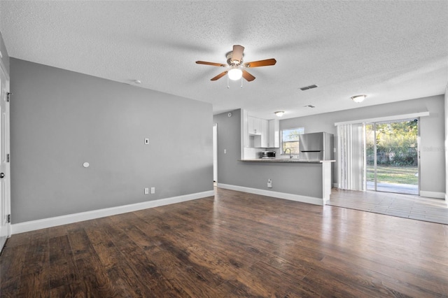 unfurnished living room with ceiling fan, dark hardwood / wood-style flooring, a textured ceiling, and sink