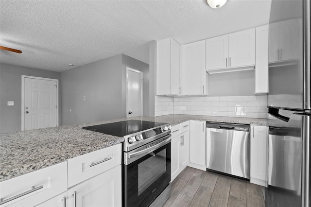 kitchen with ceiling fan, a textured ceiling, light stone counters, white cabinetry, and stainless steel appliances