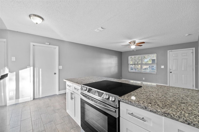 kitchen with electric range, ceiling fan, light stone counters, and white cabinetry