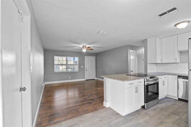 kitchen with kitchen peninsula, white cabinetry, ceiling fan, and appliances with stainless steel finishes