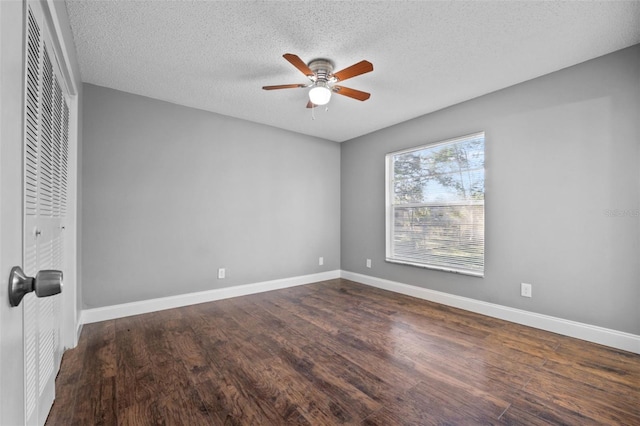 unfurnished bedroom featuring ceiling fan, a closet, dark wood-type flooring, and a textured ceiling