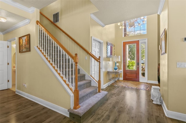 entrance foyer with crown molding, dark hardwood / wood-style flooring, a textured ceiling, and a high ceiling