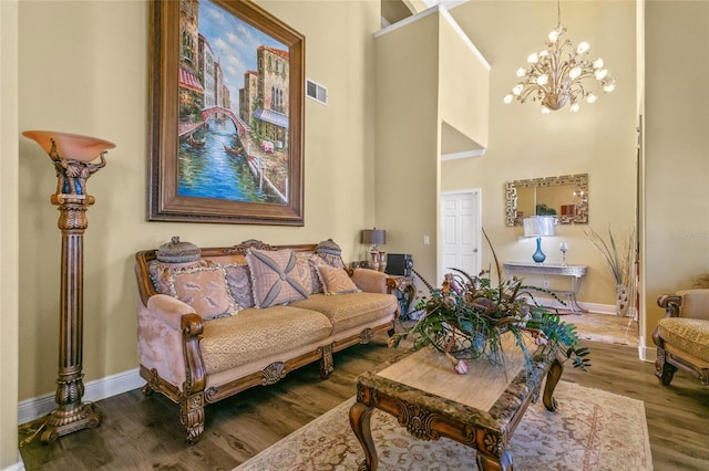 living room featuring hardwood / wood-style flooring, a chandelier, and a towering ceiling