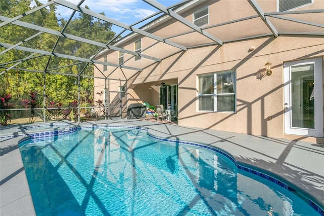 view of swimming pool featuring a patio area, an in ground hot tub, ceiling fan, and glass enclosure