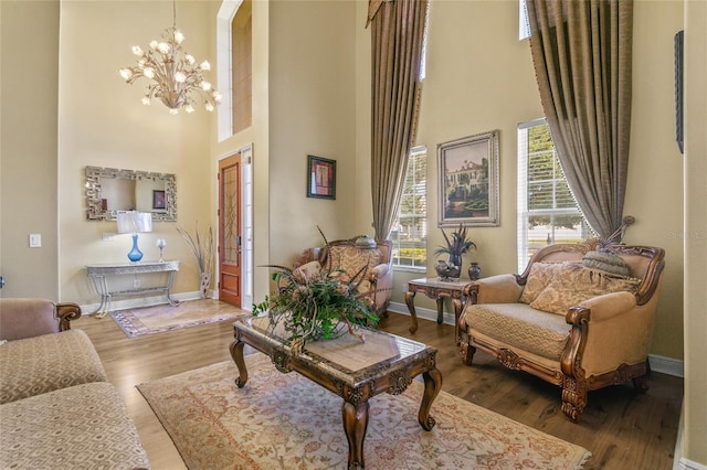 living area with hardwood / wood-style flooring, a chandelier, and a high ceiling