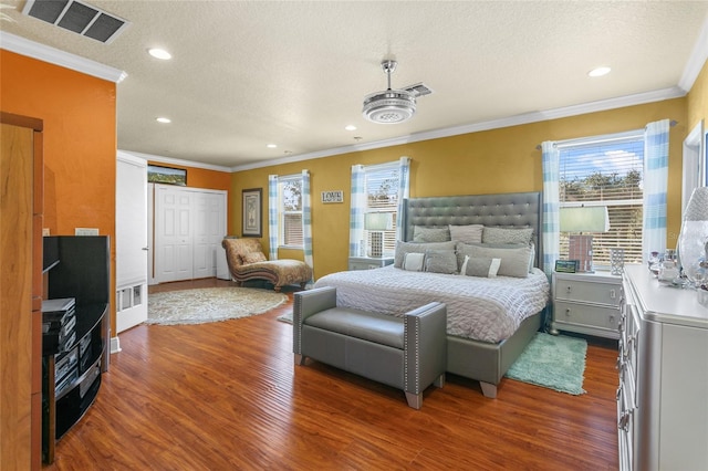 bedroom with crown molding, a textured ceiling, and dark hardwood / wood-style flooring