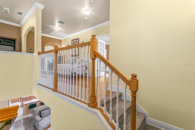 stairway featuring crown molding and a textured ceiling