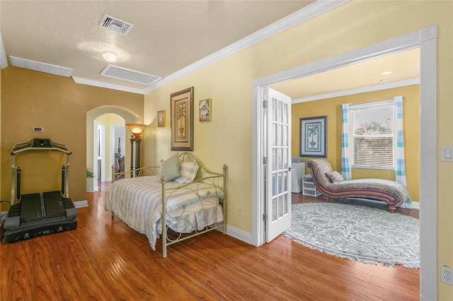 bedroom with hardwood / wood-style flooring, ornamental molding, and a textured ceiling