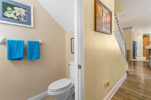 bathroom with toilet, hardwood / wood-style floors, and a textured ceiling