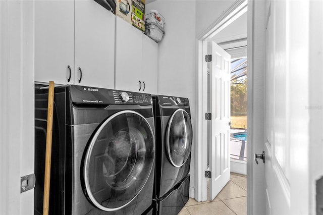 laundry room featuring light tile patterned flooring, washing machine and clothes dryer, and cabinets