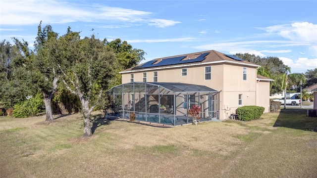 rear view of house featuring a lanai, a lawn, and solar panels