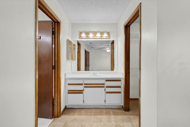 corridor with sink, light carpet, and a textured ceiling