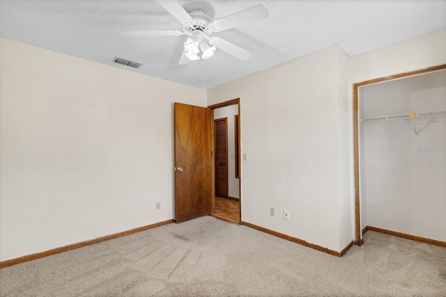 unfurnished bedroom featuring ceiling fan, light colored carpet, a closet, and a textured ceiling