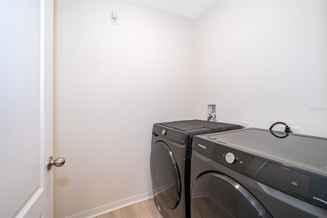 clothes washing area with washing machine and dryer and light hardwood / wood-style floors