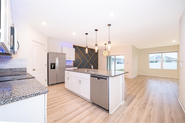 kitchen featuring pendant lighting, an island with sink, white cabinets, dark stone counters, and appliances with stainless steel finishes