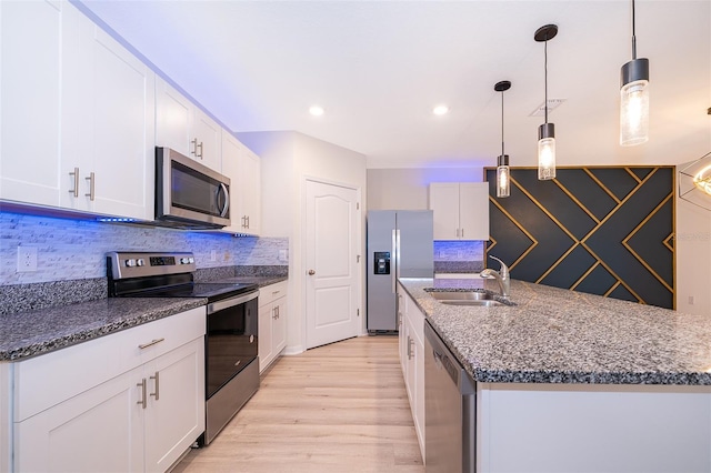 kitchen featuring appliances with stainless steel finishes, hanging light fixtures, light hardwood / wood-style floors, white cabinets, and sink