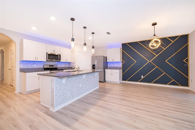 kitchen featuring stainless steel appliances, light wood-type flooring, white cabinets, and an island with sink