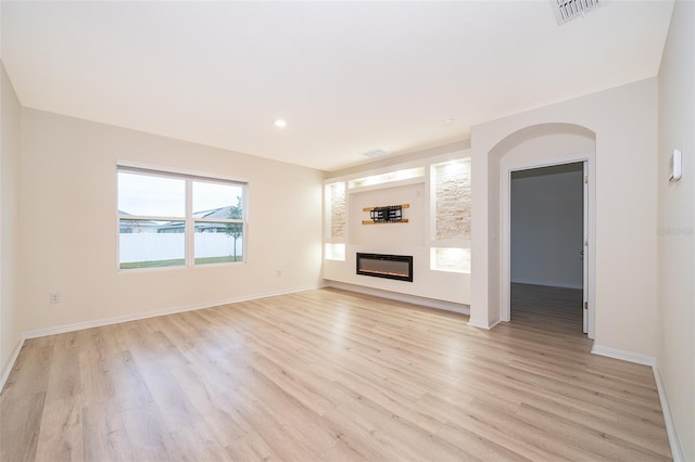 unfurnished living room with light hardwood / wood-style flooring and a water view