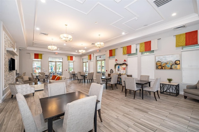 dining space with a notable chandelier, light wood-type flooring, and a tray ceiling