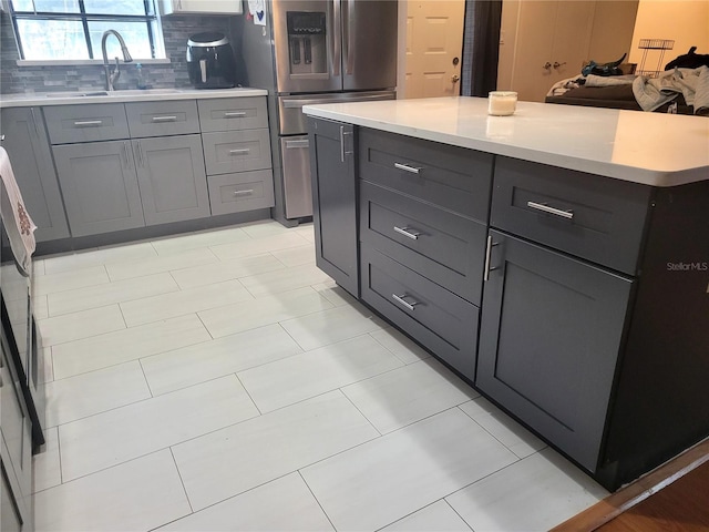 kitchen featuring sink, gray cabinetry, backsplash, a center island, and stainless steel fridge with ice dispenser