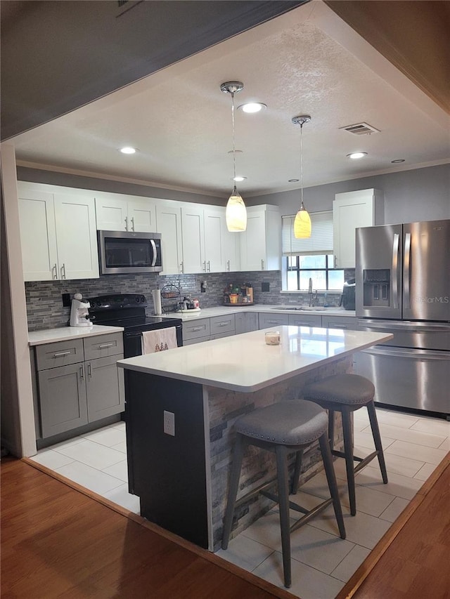 kitchen with stainless steel appliances, decorative light fixtures, a kitchen island, and white cabinets