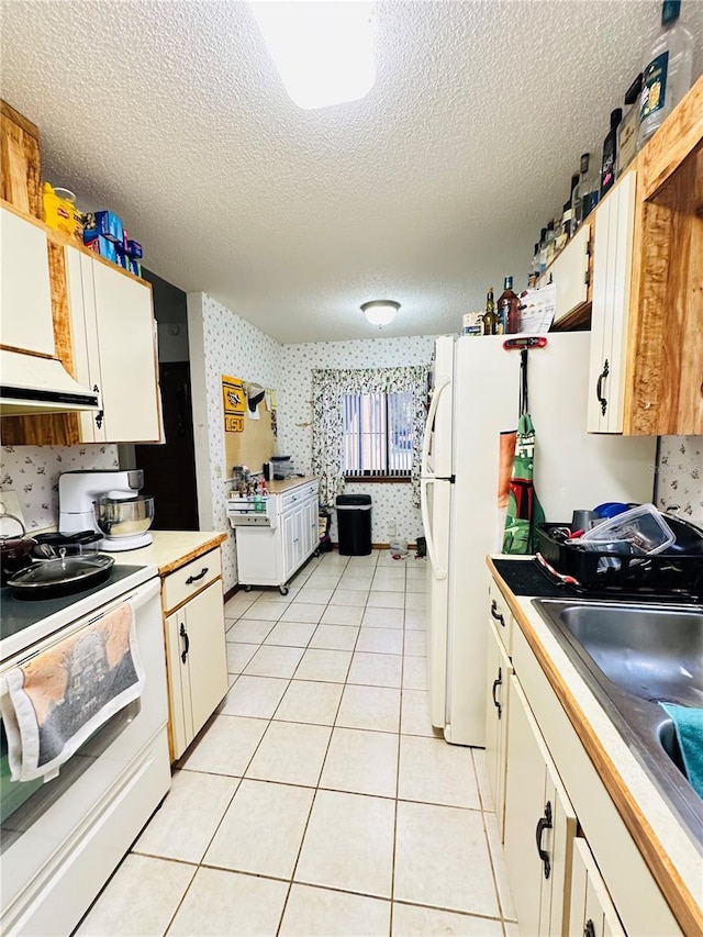 kitchen with light tile patterned floors, white cabinetry, white electric range, a textured ceiling, and sink