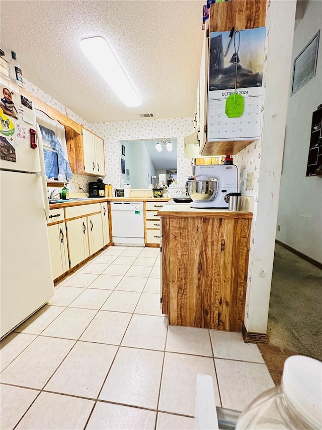 kitchen featuring kitchen peninsula, white appliances, light tile patterned floors, and a textured ceiling